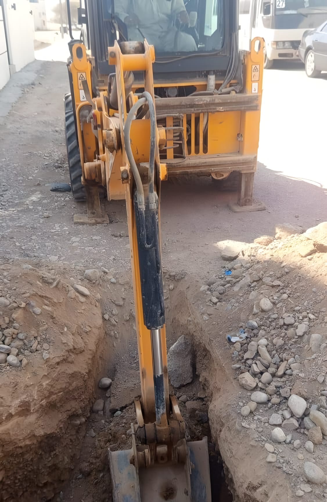 حفّارة تشق خندق خدمة في شارع سكني