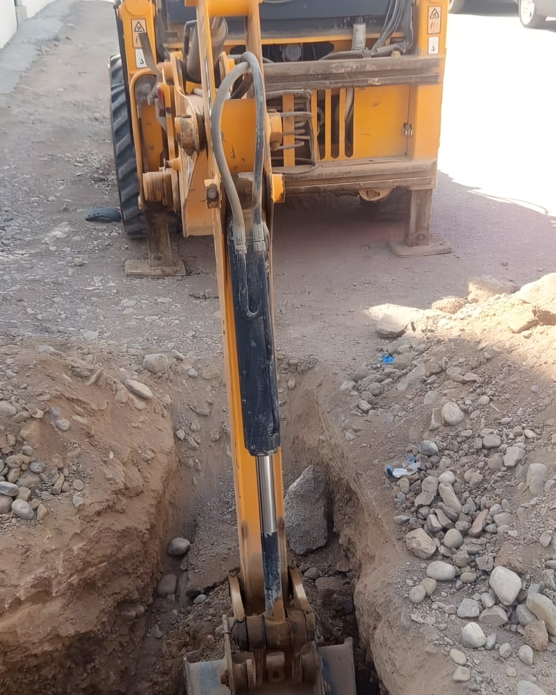 حفّارة تشق خندق خدمة في شارع سكني