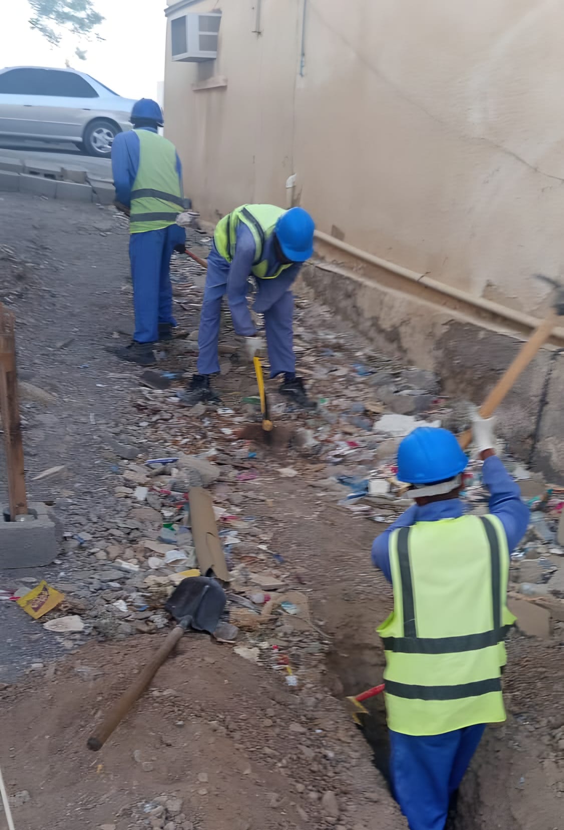 حفر يدوي بمحاذاة جدار، والطاقم بالخوذ والسترات العاكسة